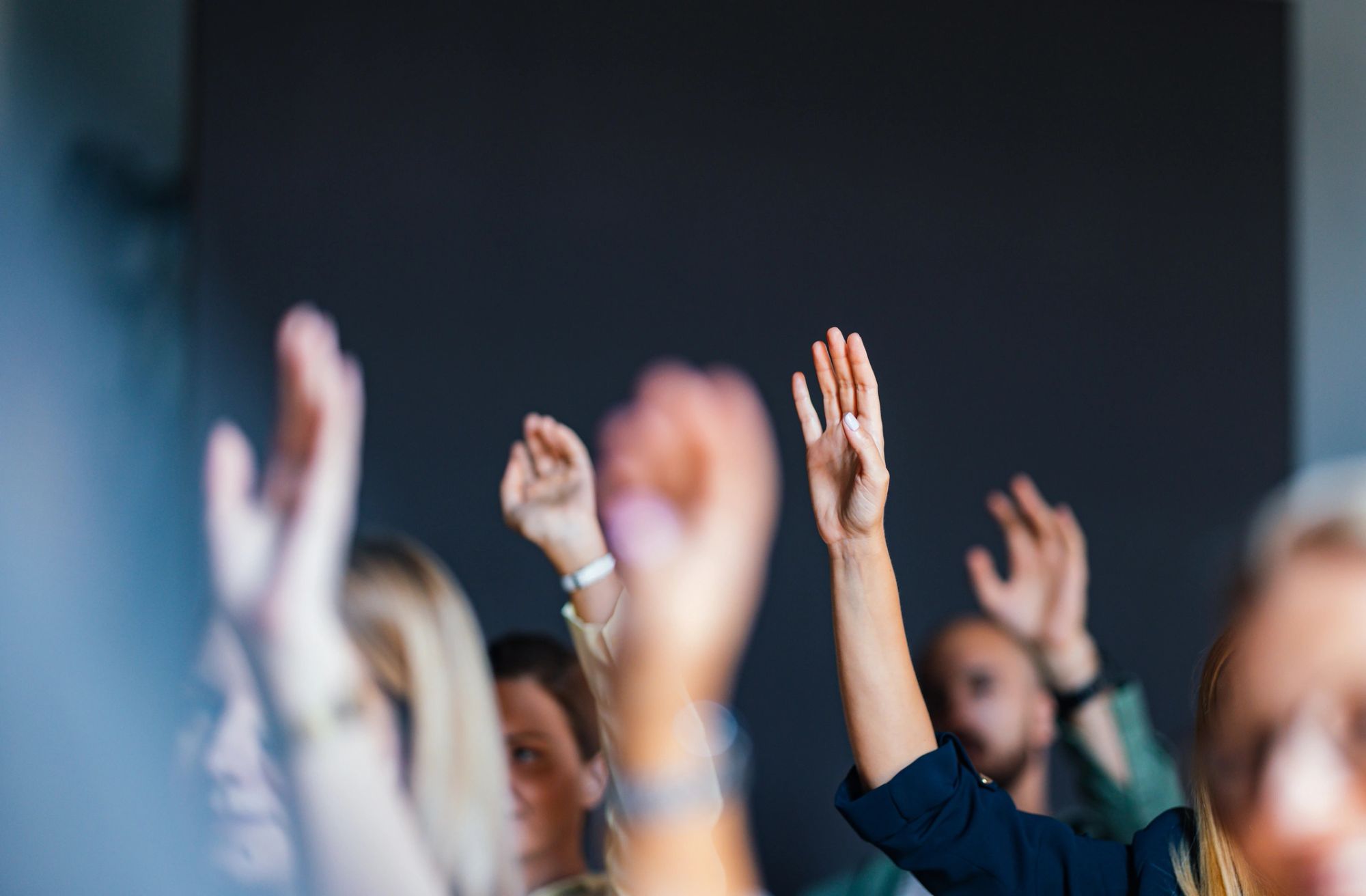 Raised hands in an audience during a public session.